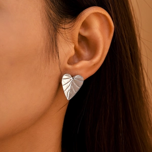 Minimalist silver stainless steel heart leaf pattern stud earrings on female model