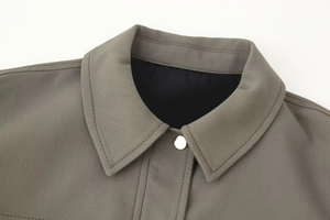 Detail of army green bomber jacket collar with silver metal snap buttons and twill fabric