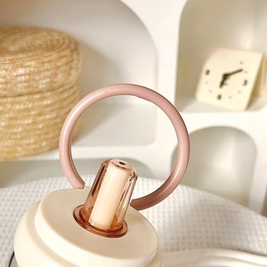 Detail of pink portable carry loop and transparent straw on modern glass water bottle lid