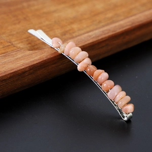 Close-up of silver metal hairpin with natural orange-pink crushed crystal stones