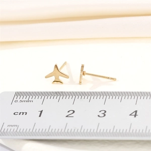Golden airplane stud earrings in stainless steel with measurement scale on white background