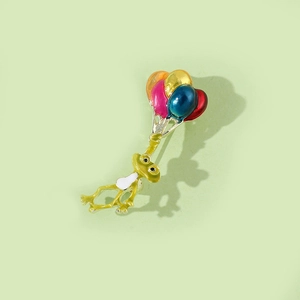 Détail de la broche créative grenouille verte tenant des ballons colorés au fini métallique