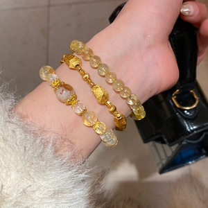 Detail of layered gold beaded bracelets with citrine crystal and floral zircon on wrist