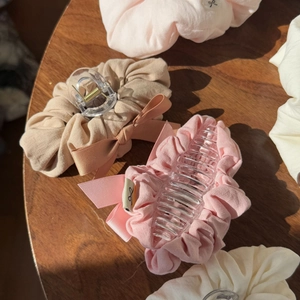 Detail of large fabric bow shark hair clips in pink and beige colors on wooden table