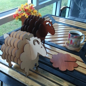 Outdoor close-up of sheep-shaped wooden coaster set with flower-patterned mats