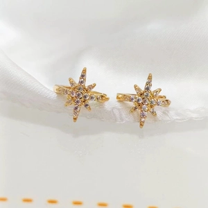 Elegant gold star stud earrings with cubic zirconia on white silk background