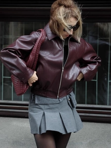 Veste en cuir rouge foncé pour femme avec jupe plissée grise dans un style urbain chic