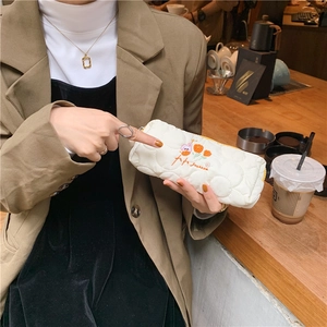 Detail of white quilted pen bag with orange tulip embroidery held in hands