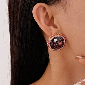 Vue macro de la boucle d'oreille ronde vintage avec texture dorée et strass roses
