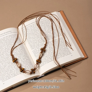 Close-up of bohemian woven belt with natural shells and beads on vintage book pages