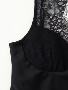 Detailed close-up of delicate floral lace and smooth satin fabric on black camisole top