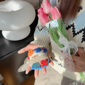 Detail of beige plush bucket bag with colorful floral embroidery and pearl charm accessory
