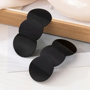 Modern geometric earrings with three black circular discs in a stylish layered design