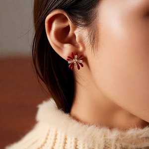 Close-up of 18k gold flower earrings with red petals and zircon crystals on model