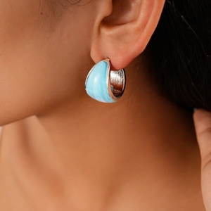 Close-up of sky blue resin marble hoop earrings with silver edges worn by model