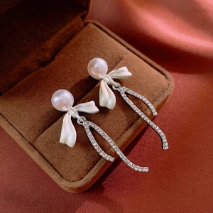 Detail view of bowknot pearl earrings with sparkling rhinestones in a luxury jewelry box