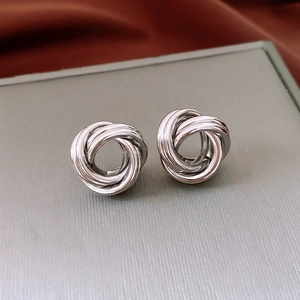 Vue macro de boucles d'oreilles nœud en métal argenté avec finition polie et triple tissage