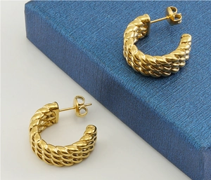 Macro shot of twisted 18k gold hoop earrings with intricate metal braiding detail