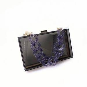 Detail view of smoky gray acrylic handbag with purple resin chain and gold clasp