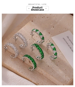 Détail de boucles d'oreilles en titane avec zircons triangulaires verts et blancs