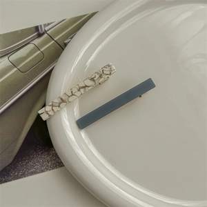 Detail of French acetate hair clips in shell white and navy blue on a ceramic plate