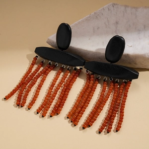 Detail view of retro wood texture earrings with orange beaded tassels and matte black studs