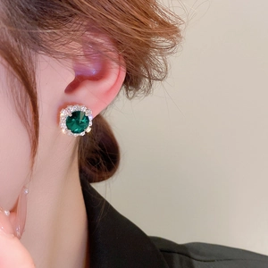 Detailaufnahme eleganter smaragdgrüner Halo-Ohrstecker am Model mit Silberauflage