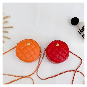 Close-up of mini quilted round bags in orange and red with golden flower details