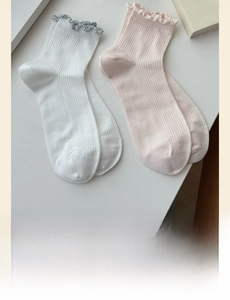 Detail of cotton crew socks with ruffle cuffs and vertical ribbed texture in soft colors