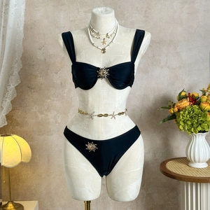 Détail d'un bikini noir avec des boucles en métal doré sur le haut et le bas du maillot