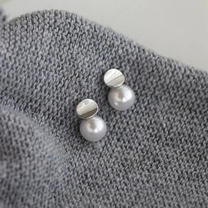 French style irregular pearl stud earrings with silver metal disks on grey background