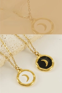 Detail of gold moon crescent pendant with black and white enamel on a wave-edge circle