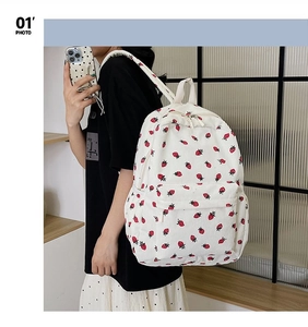 Side view of cream corduroy backpack with red strawberry patterns on a female model