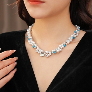 Dettaglio di una collana vintage con perle bianche e pietre turchesi in grappolo floreale