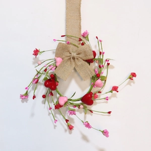 Close-up of pink flowers, heart ornaments, and a burlap bow on a Valentine candle ring