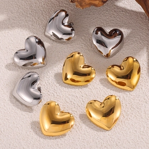 Elegante Herz-Ohrstecker in Gold und Silber poliert auf strukturierter Steinoberfläche