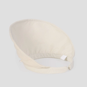 Detail of beige sun visor hat featuring a decorative pearl and woven fabric texture
