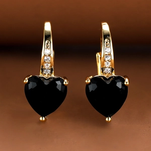 Macro detail of heart-cut black gemstone earrings with gold plating and clear cubic zirconia