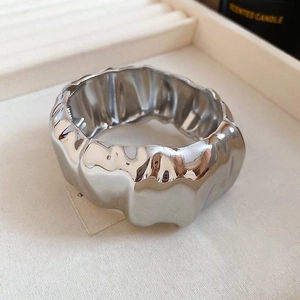 Détail d'un large bracelet manchette argenté avec texture ondulée en métal liquide