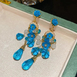Gros plan de boucles d'oreilles vintage fleurs bleues et cristaux dans un écrin à bijoux