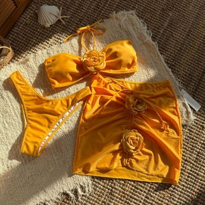 Macro shot of 3D rose floral details on a bright orange three-piece bikini set