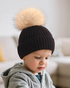 Detailed close-up of children black ribbed knit hat with large soft brown faux fur pompom