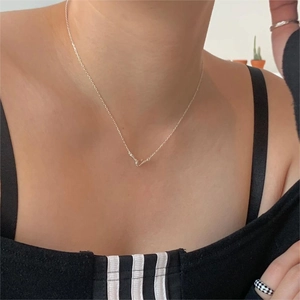 Close-up of minimalist 925 silver necklace featuring a slender curved pendant on the collarbone