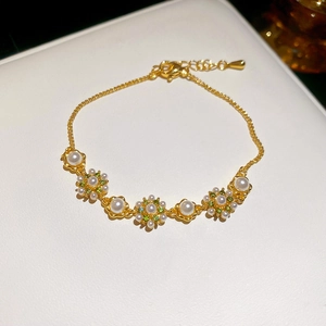 Detail eines vergoldeten Blumenarmbands mit Perlen und grünen Steinen auf Leder