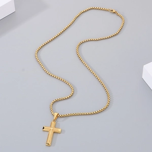 Macro detail of golden stainless steel cross pendant with textured engraving on box chain
