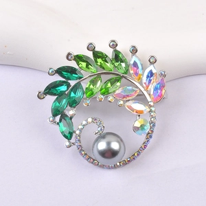 Detailed view of luxury leaf brooch featuring green crystals and a large grey pearl