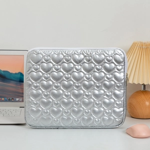 Close-up of quilted heart pattern on silver laptop sleeve with desktop setup