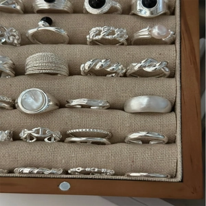 Adjustable silver ring set with black agate stones displayed in a wooden linen tray