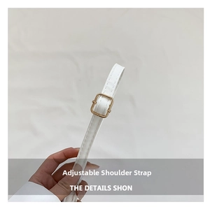 Close-up of white adjustable shoulder strap with golden metal buckle and stitching