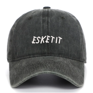 Detail shot of white ESKETIT embroidery on a dark grey washed cotton baseball cap